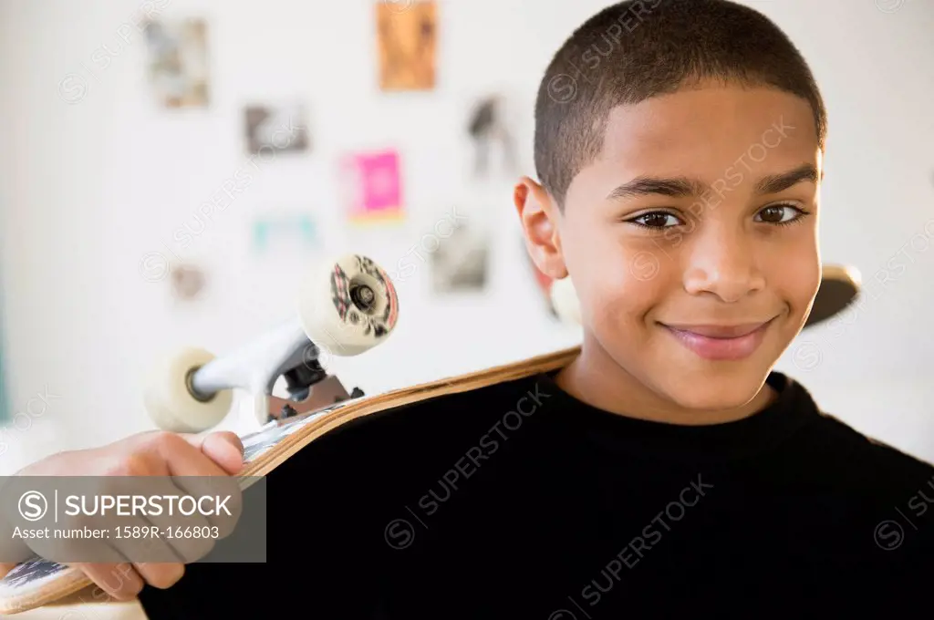 Hispanic boy holding skateboard