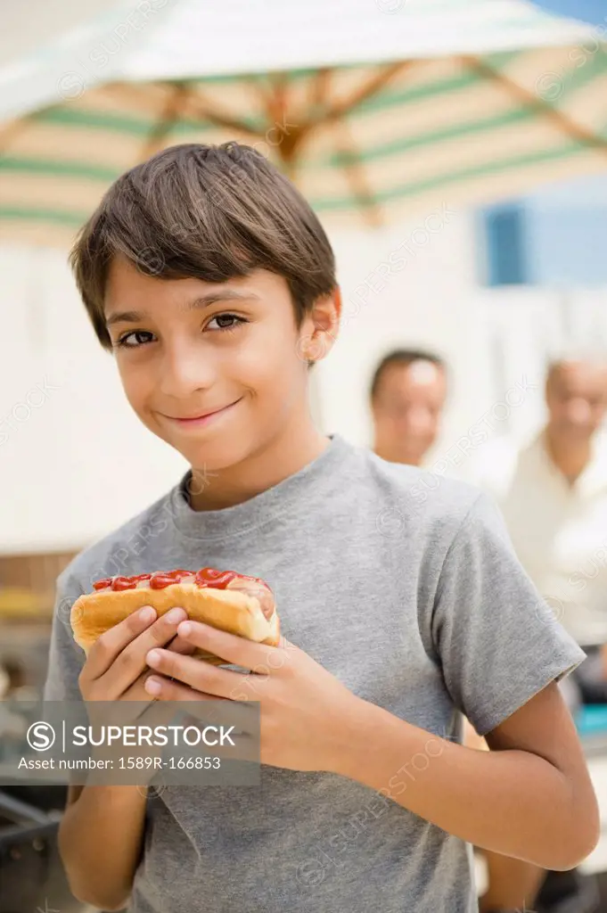 Hispanic boy eating hot dog