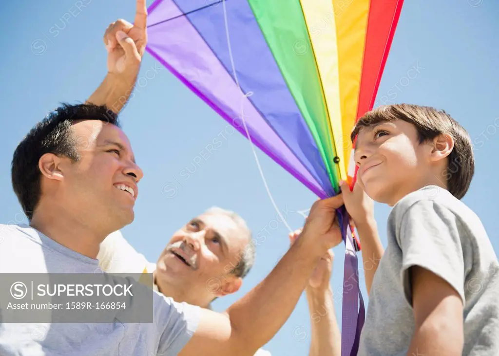 Hispanic grandfather, father and son flying kite