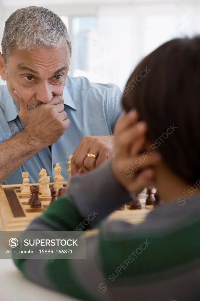 Hispanic grandfather and grandson playing chess