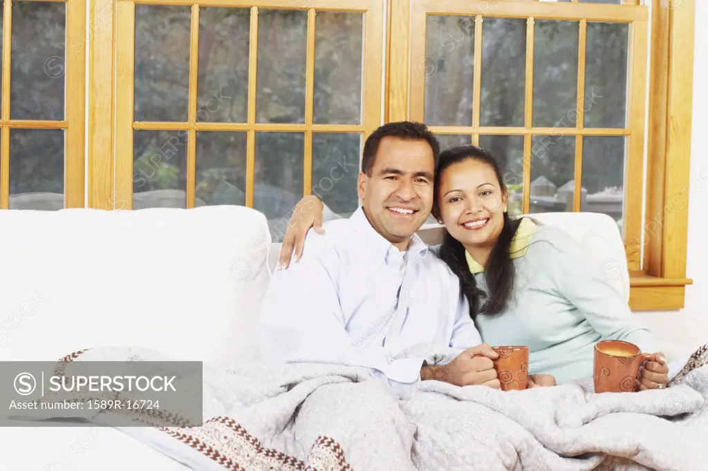 Couple sitting on the couch under a blanket together