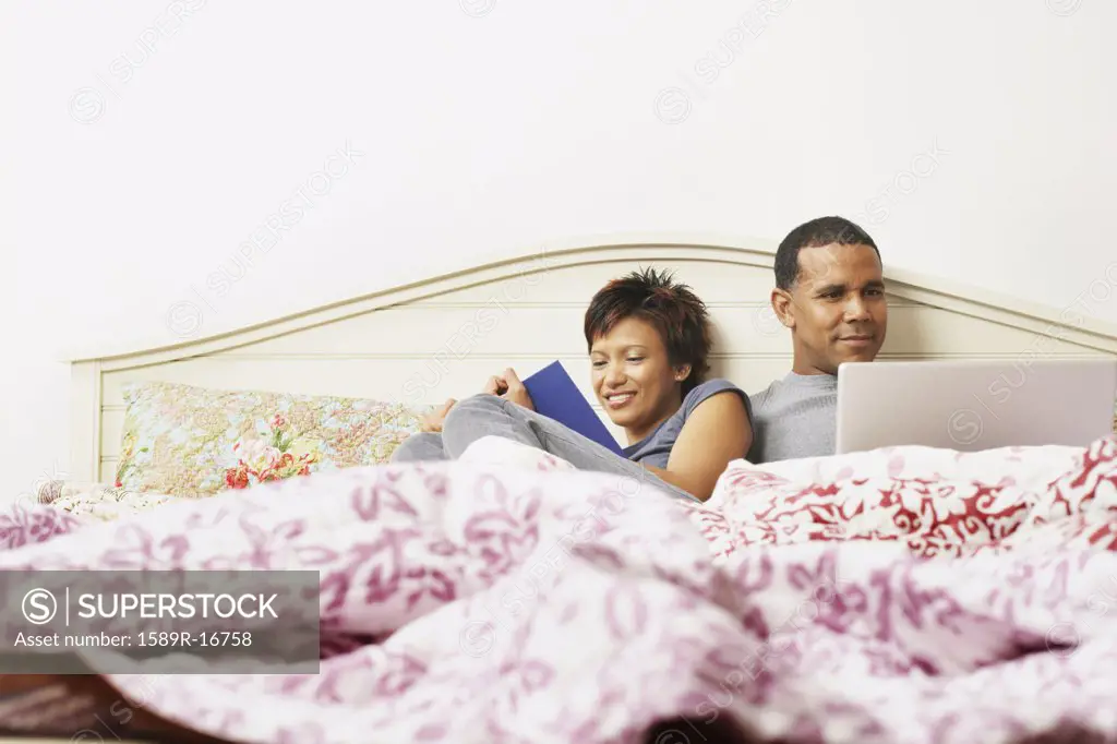 Couple using a laptop in bed