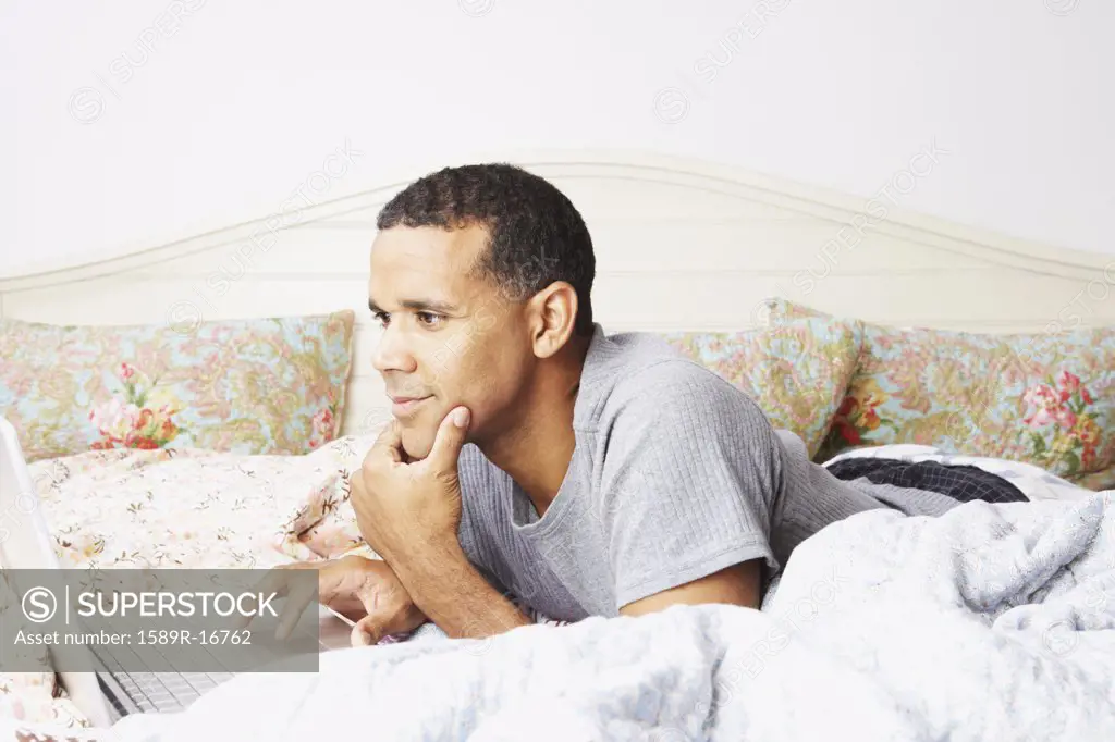 Man using a laptop in bed