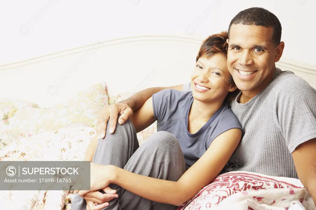 Young couple smiling for the camera in bed