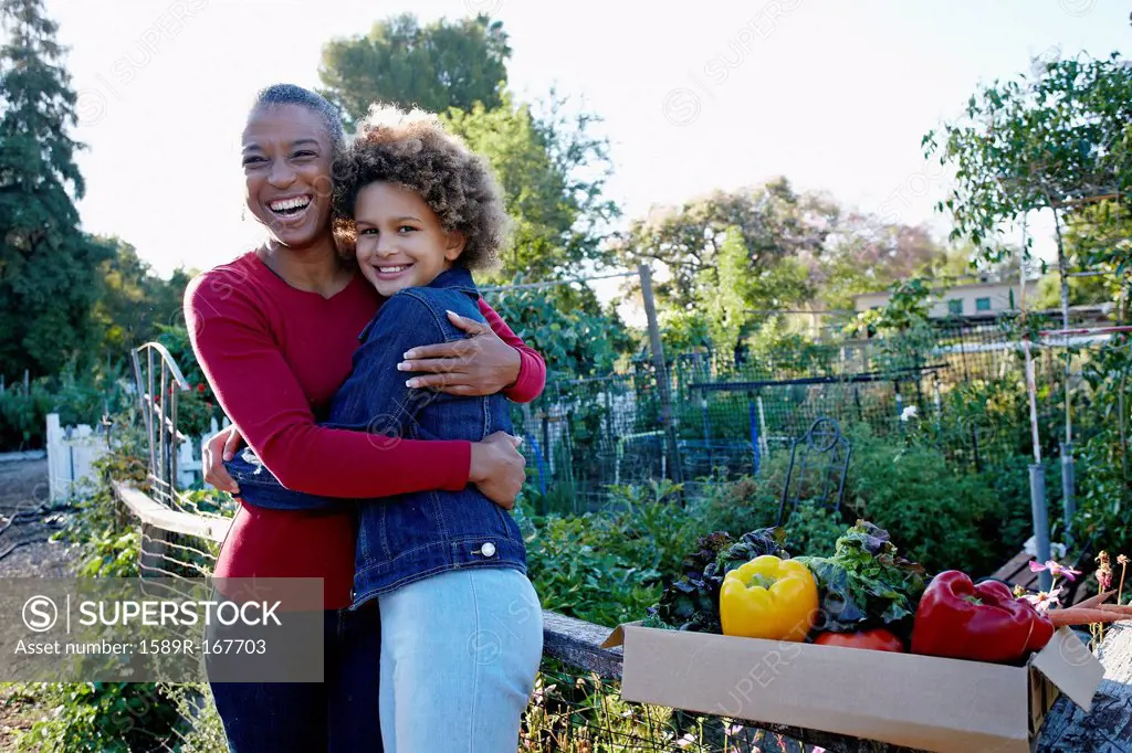 Mother and daughter gathering vegetables in community garden