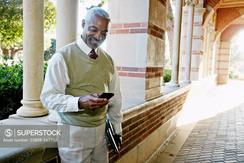 Black professor text messaging on cell phone