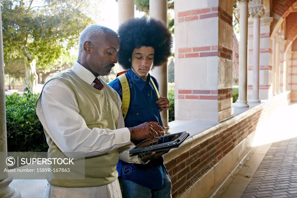 Professor with digital tablet talking to student