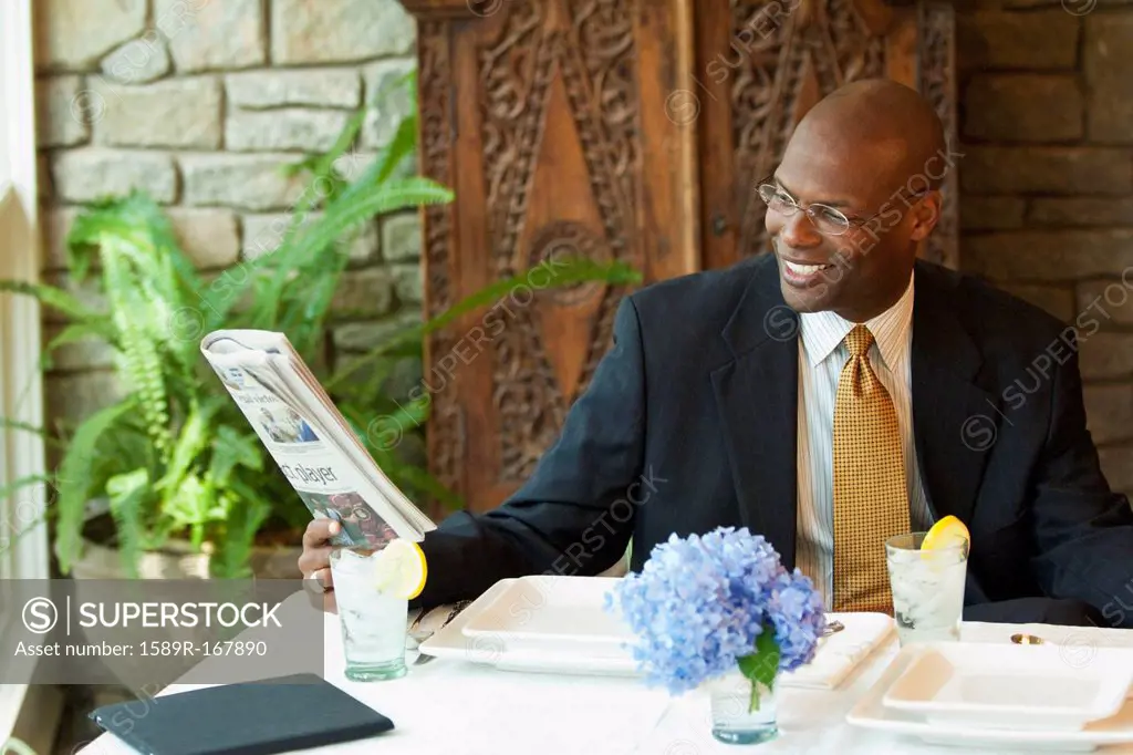 Black businessman reading newspaper in restaurant