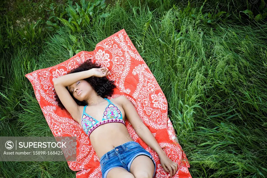 Hispanic woman laying in grass taking nap