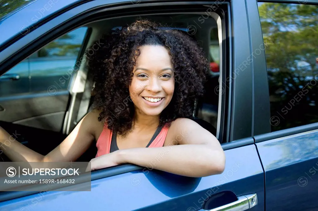 Smiling Hispanic woman driving car
