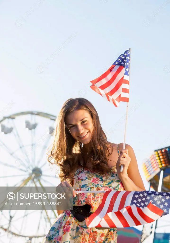 Caucasian woman holding American flags at carnival