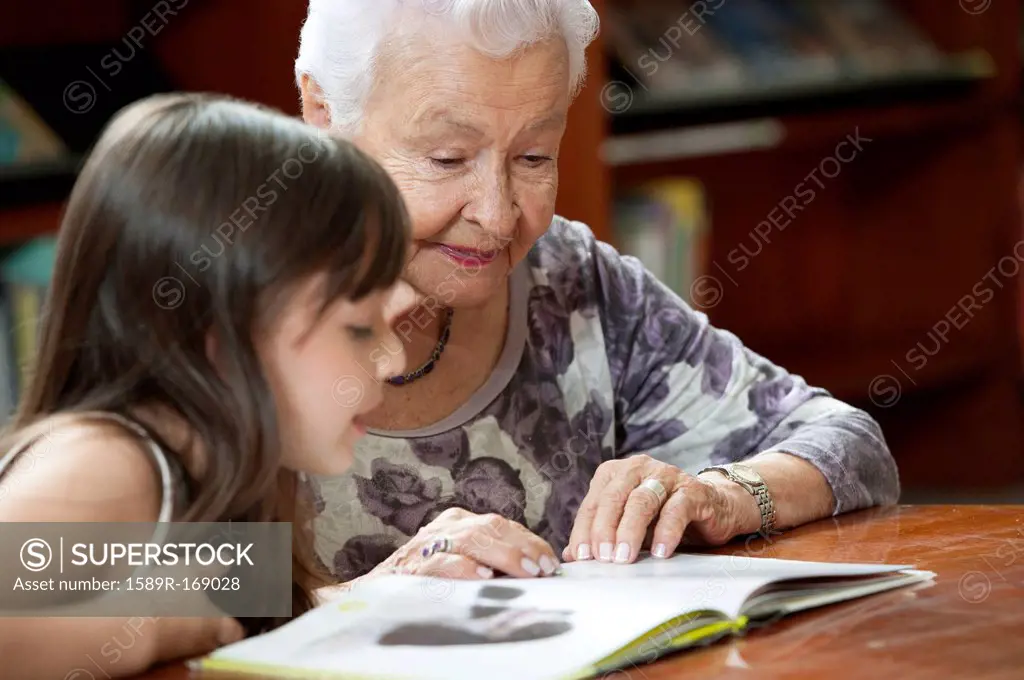 Hispanic grandmother reading book to granddaughter