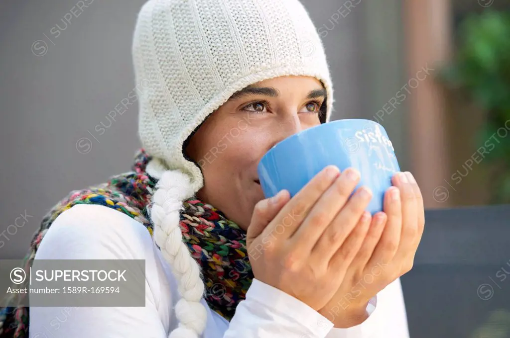 Hispanic woman drinking coffee outdoors