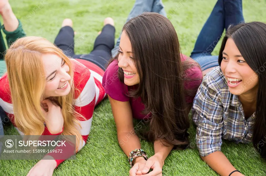Smiling women laying in grass together