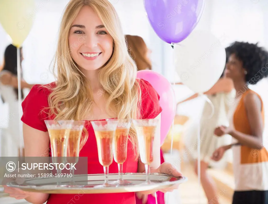 Smiling woman carrying tray of champagne