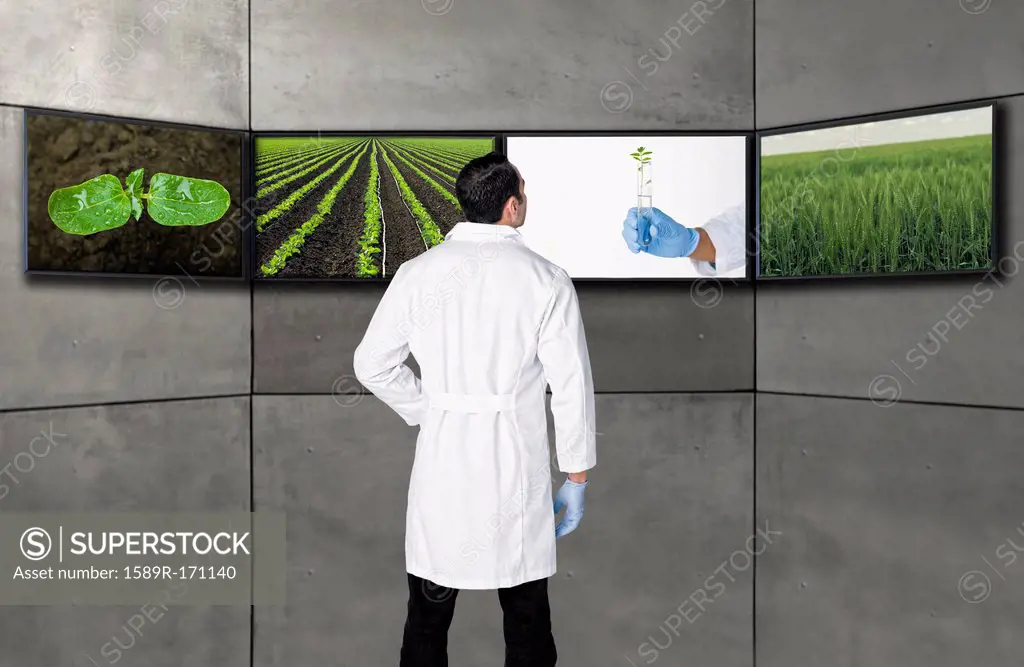 Hispanic scientist looking at images on television screens