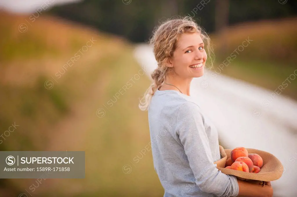 Caucasian woman picking fruit on rural road