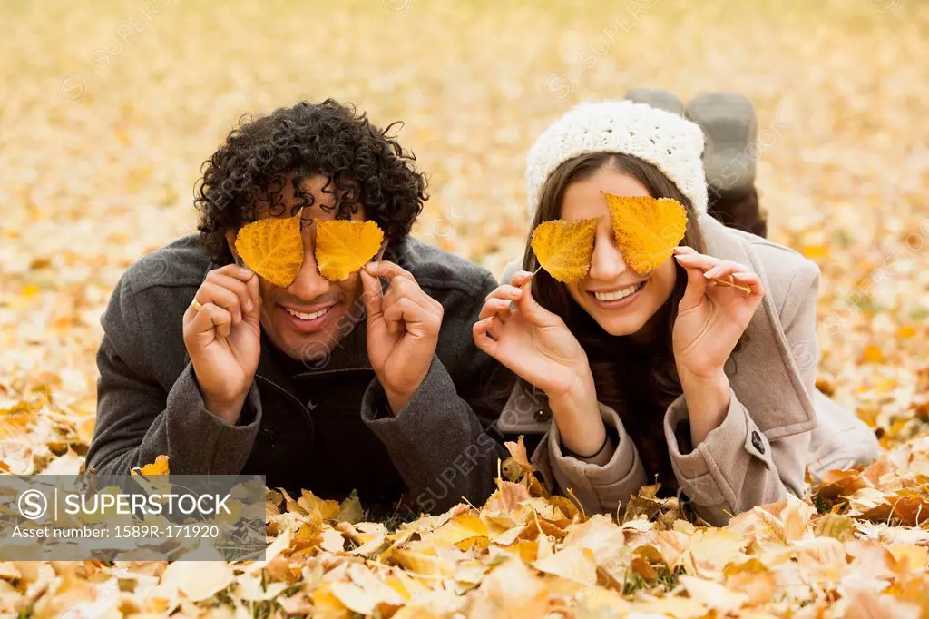 Couple playing in autumn leaves