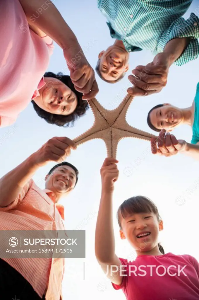 Chinese family holding starfish on beach