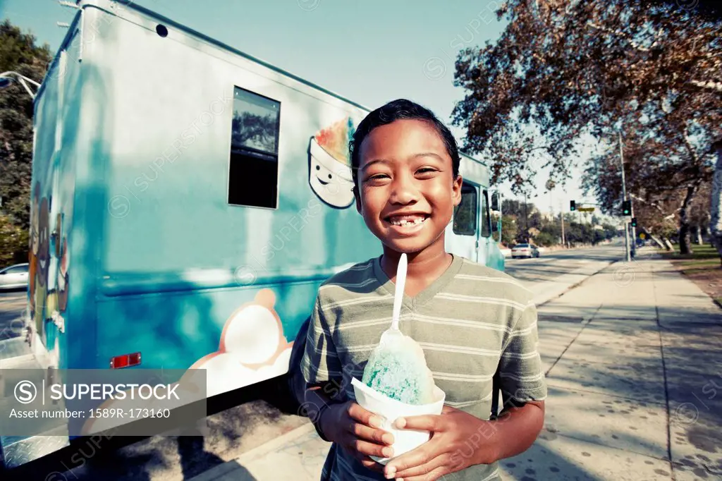Mixed race boy eating ice cream from truck