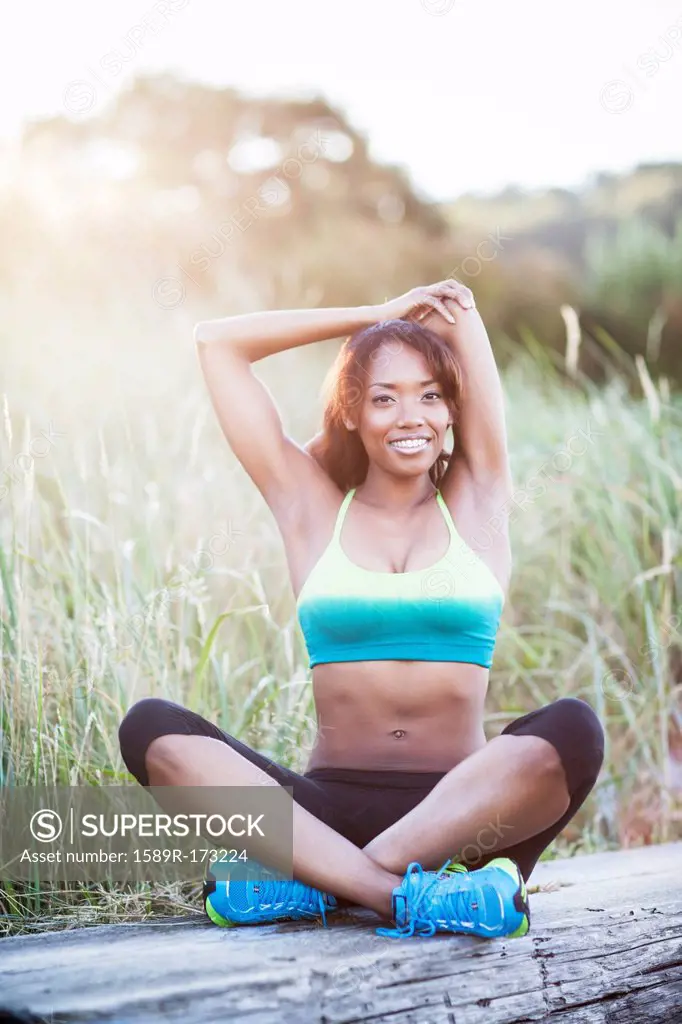 Mixed race woman stretching in field
