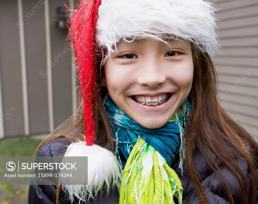 Mixed race girl in braces wearing Santa hat