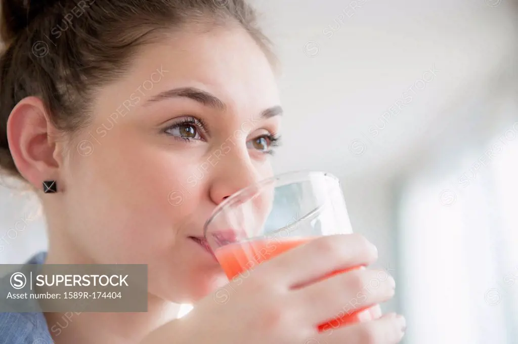 Hispanic girl drinking glass of juice