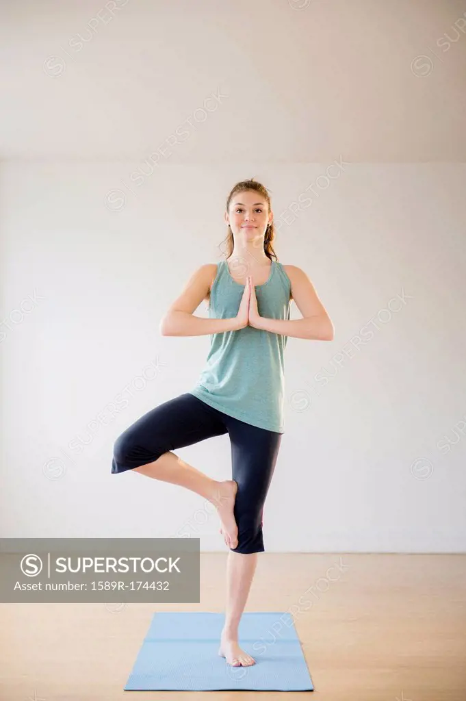 Hispanic girl practicing yoga in studio