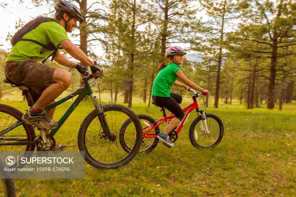 Family riding mountain bikes in meadow