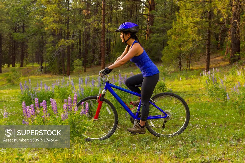 Chinese woman riding mountain bike in meadow