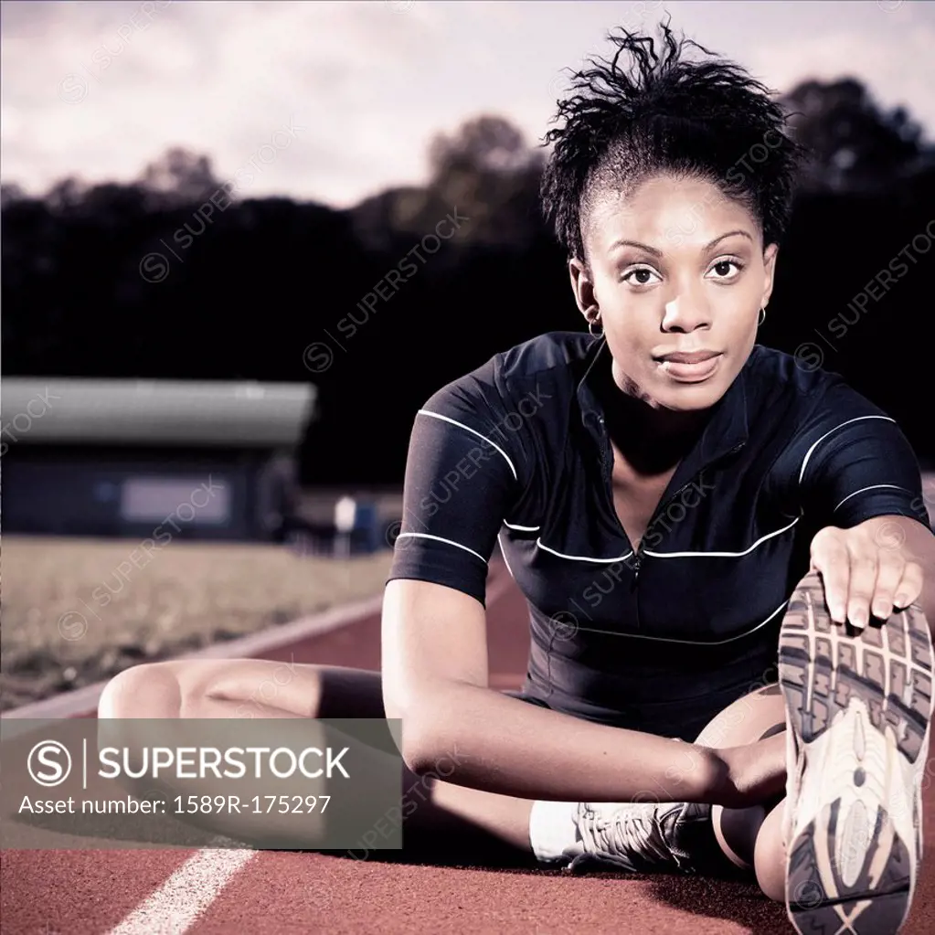 African American runner stretching on track