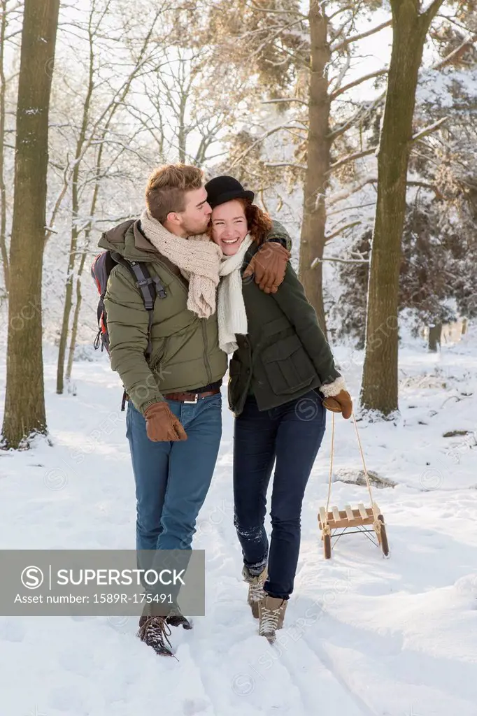 Caucasian couple pulling sled in snow