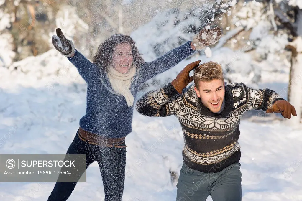 Caucasian couple playing in snow