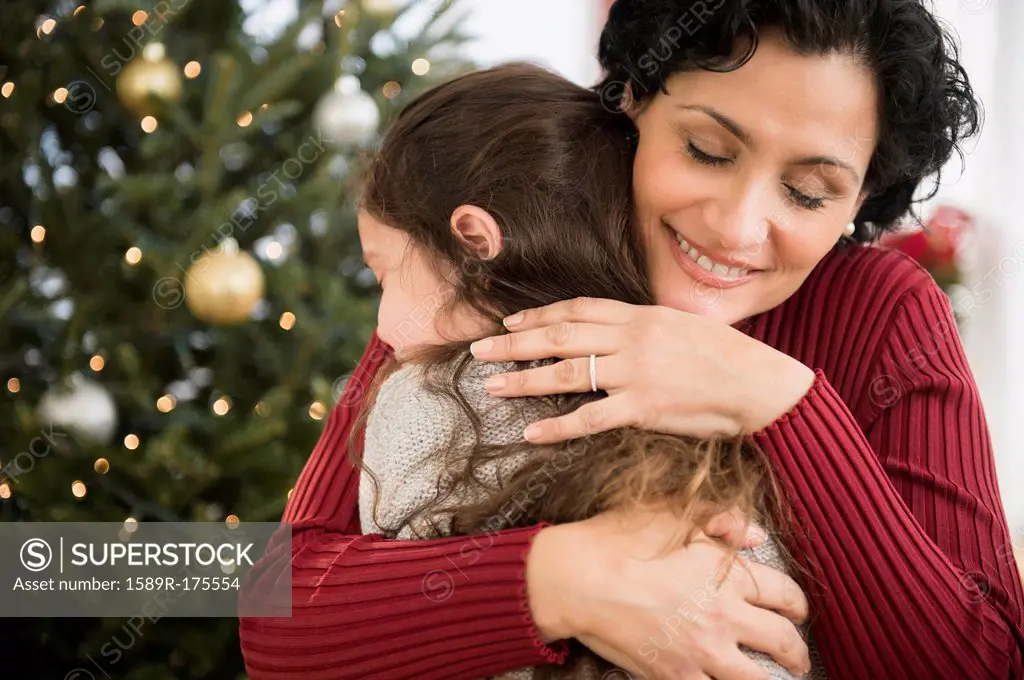 Mother and daughter hugging by Christmas tree