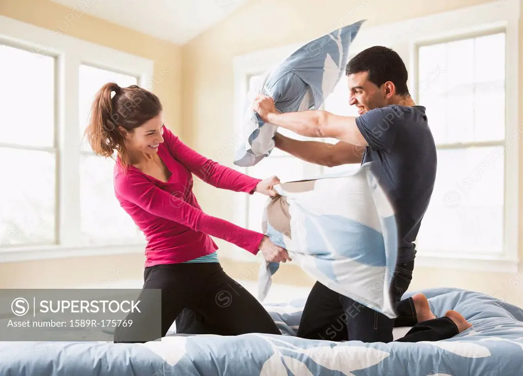 Couple having pillow fight on bed