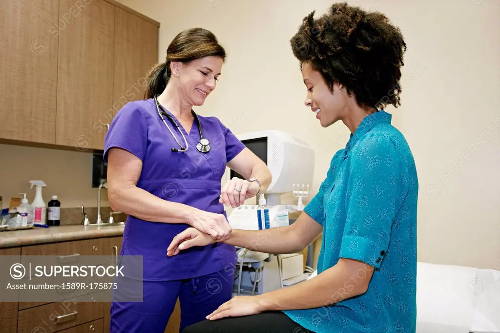 Nurse checking patient's pulse in office