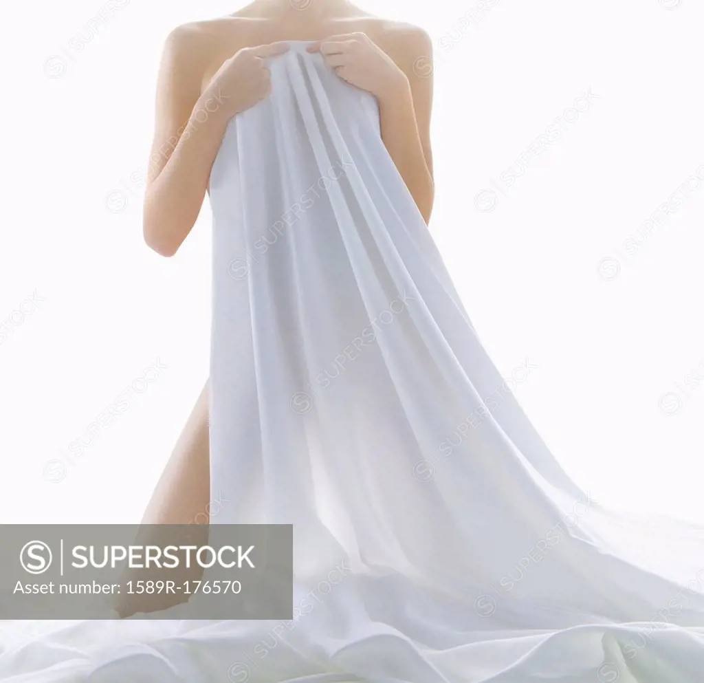 Nude woman covering herself with sheet