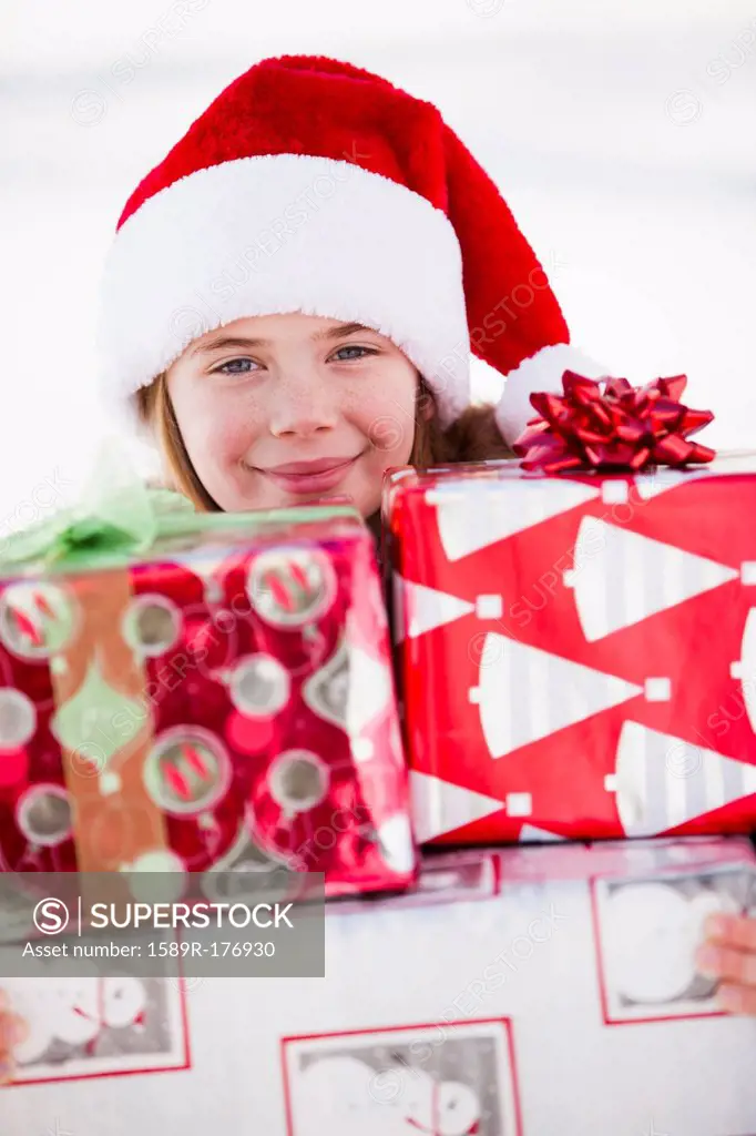 Caucasian boy in Santa hat holding Christmas presents