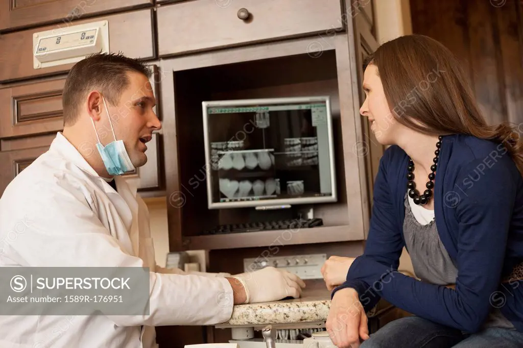 Caucasian dentist and woman talking in office