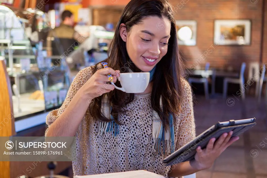 Mixed race woman using tablet computer in coffee shop