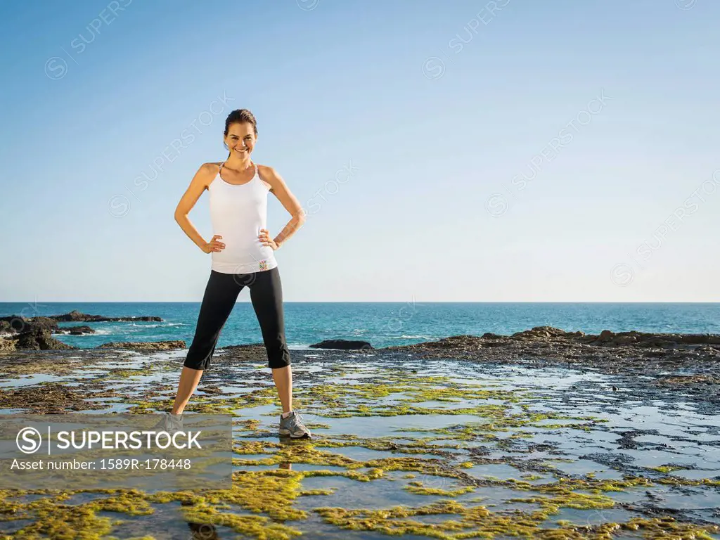 Mixed race runner standing on rocky beach