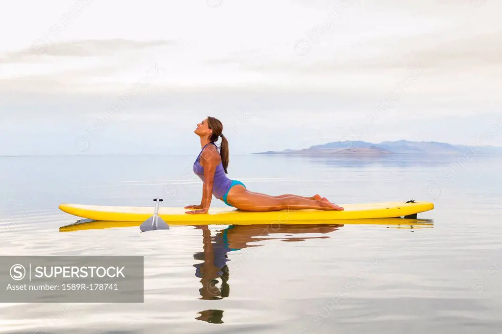 Filipino woman practicing yoga on paddle board