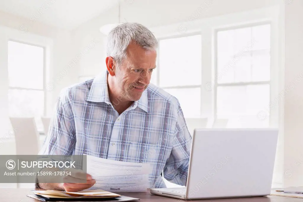 Caucasian man paying bills with laptop