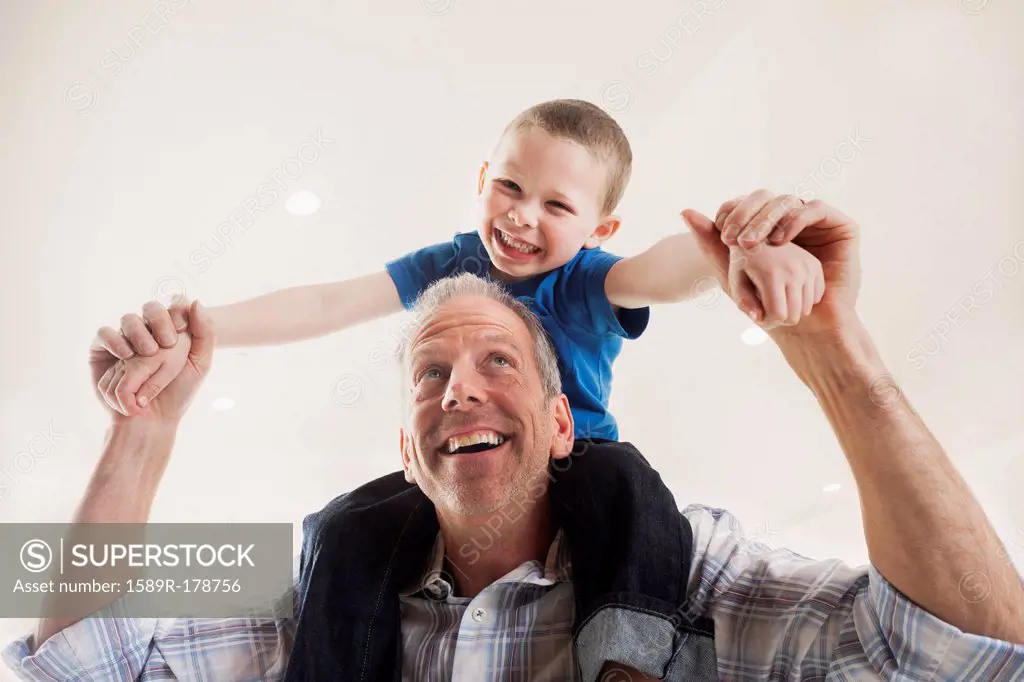 Caucasian man carrying son on shoulders