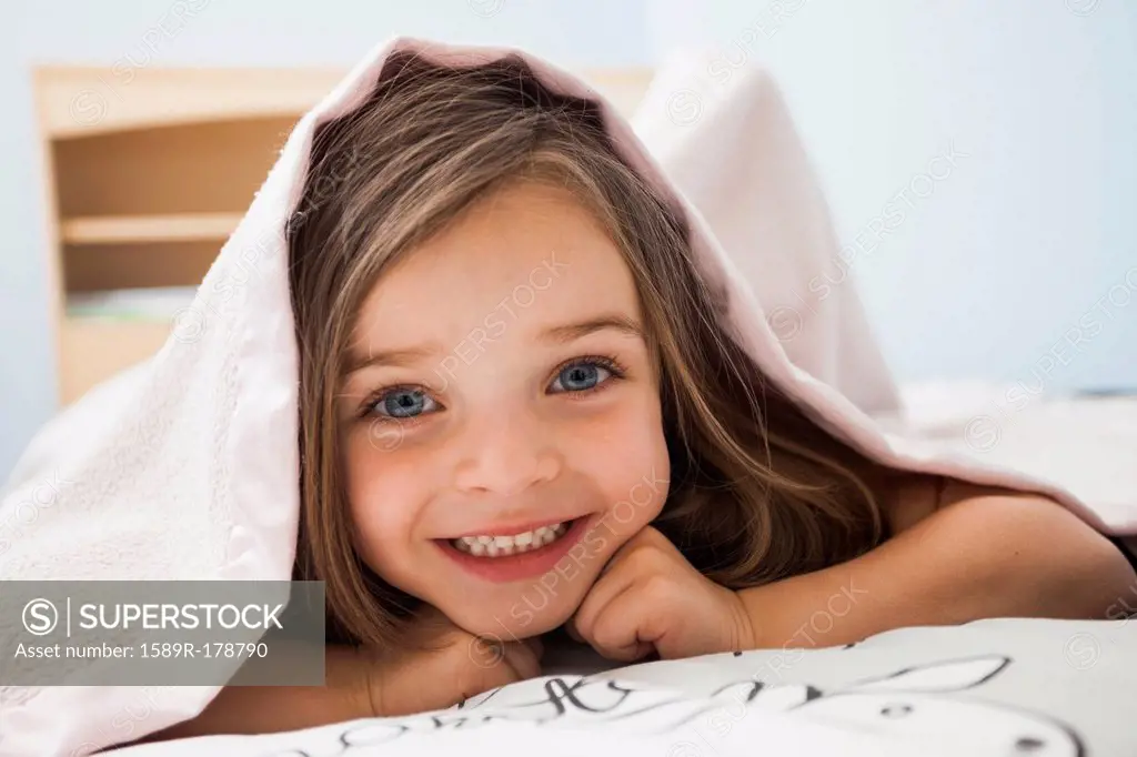 Caucasian girl smiling under covers