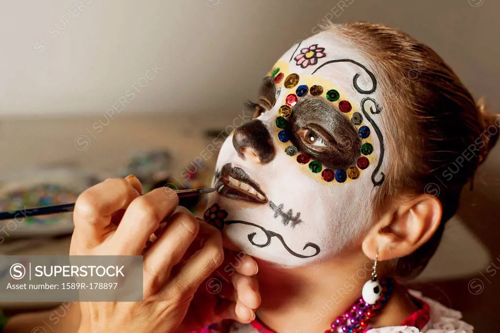 Girl having face painted for Dia de los Muertos