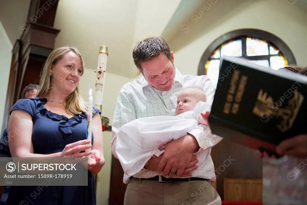 Caucasian parents having baby baptized in church