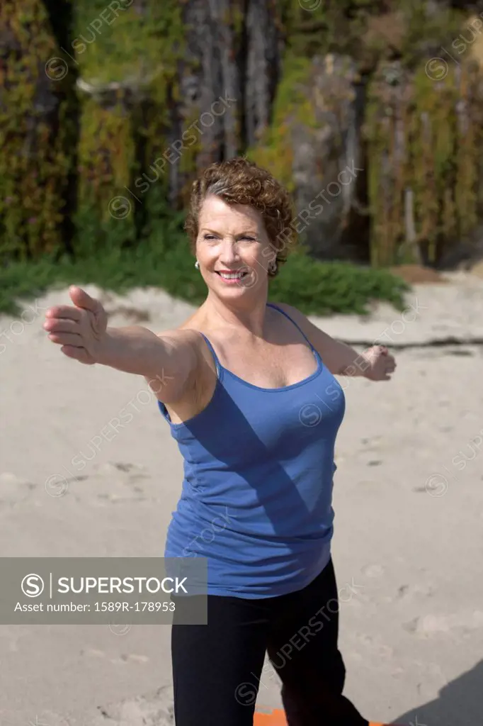 Caucasian woman practicing yoga on beach