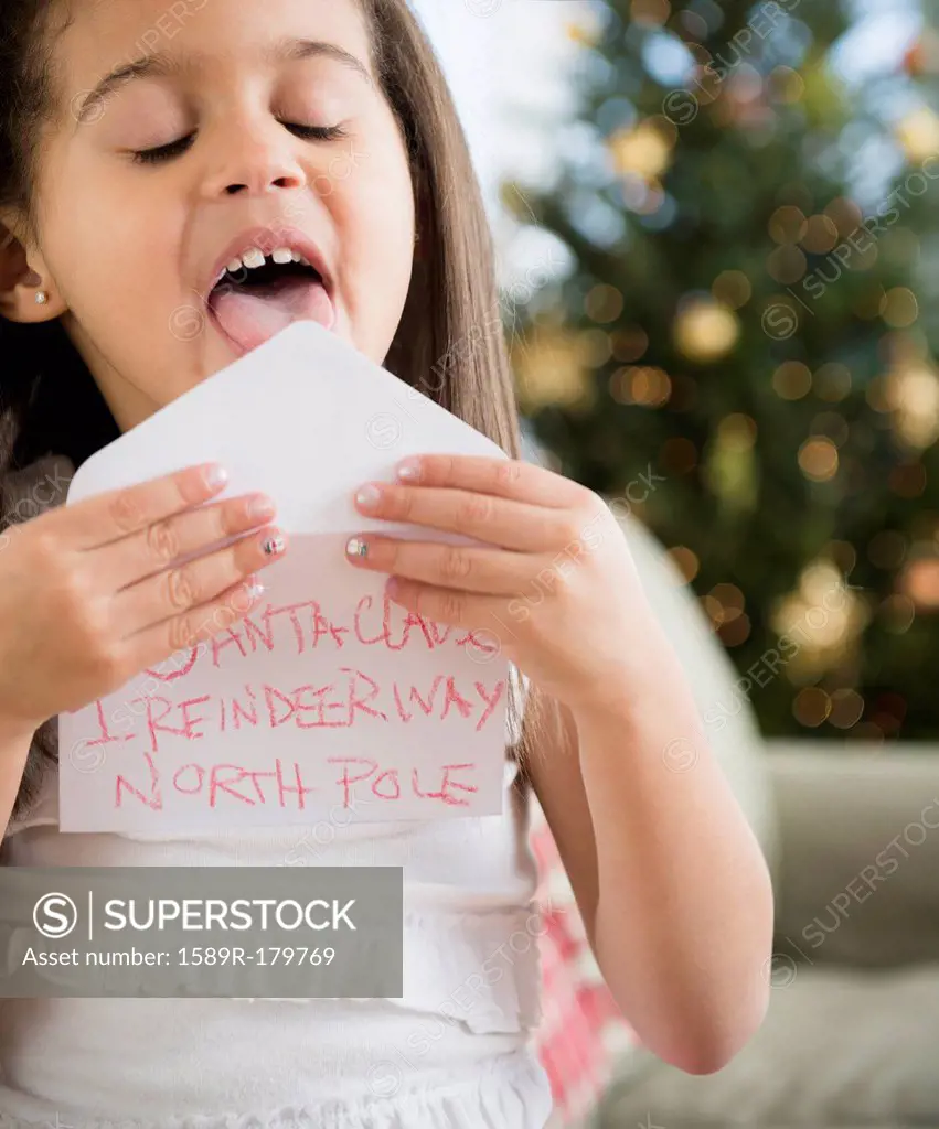 Hispanic girl sealing envelope for Santa