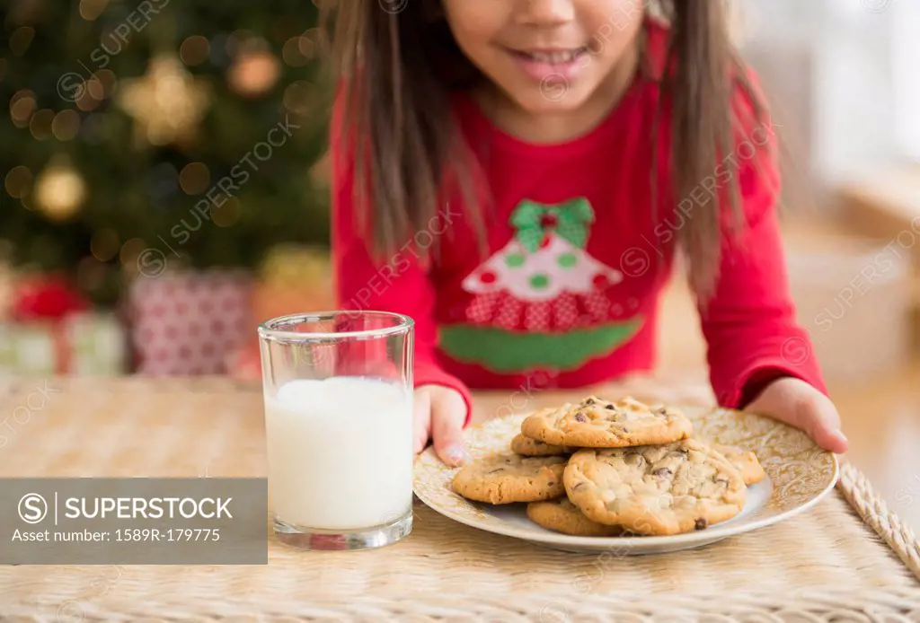 Hispanic girl setting out milk and cookies for Santa